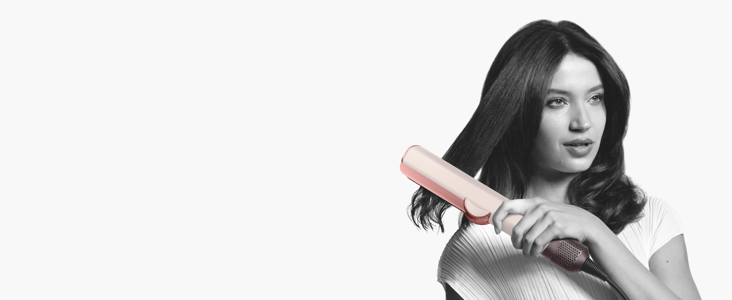 Model straightening hair with Dyson Airstrait hair straightener in ceramic pink and rose gold